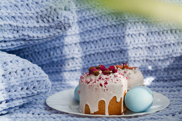 Easter bread, cake and eggs with decor of flowers, beads and nuts. Blue knitted plaid. The concept of the Easter holidays and decor.