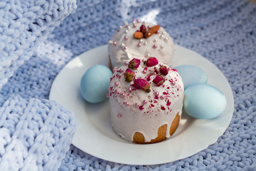 Easter bread, cake and eggs with decor of flowers, beads and nuts. Blue knitted plaid. The concept of the Easter holidays and decor.