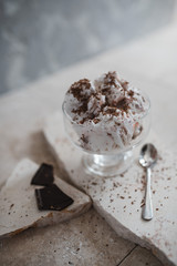 vanilla-strawberry ice cream with chocolate chips in an ice cream cone on a stone base. Gray concrete background