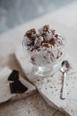 vanilla-strawberry ice cream with chocolate chips in an ice cream cone on a stone base. Gray concrete background