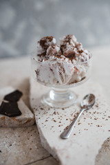 vanilla-strawberry ice cream with chocolate chips in an ice cream cone on a stone base. Gray concrete background