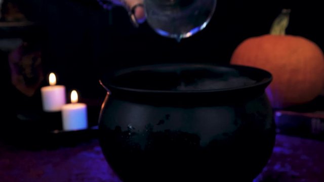 Magical Witch mixes potions in cauldron close up