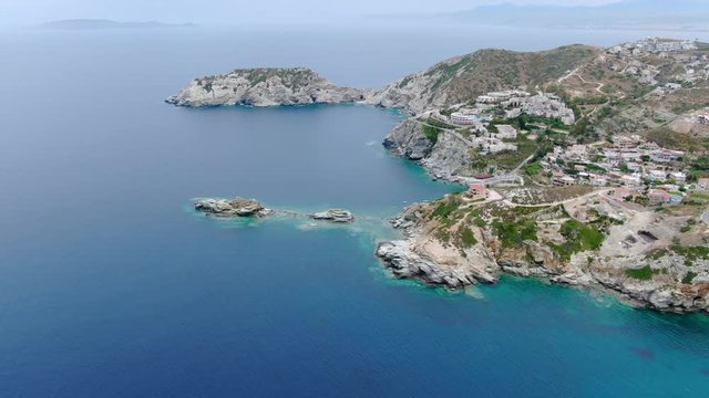 Wide angle dolly in drone aerial shot of beautiful beaches, houses, hills, and mountains in Creta Islands, Greece during the day