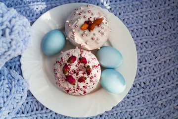 Easter bread, cake and eggs with decor of flowers, beads and nuts. Blue knitted plaid. The concept of the Easter holidays and decor.