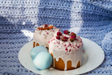 Easter bread, cake and eggs with decor of flowers, beads and nuts. Blue knitted plaid. The concept of the Easter holidays and decor.