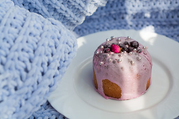 Cake with flowers, beads and nuts. Blue knitted plaid. Cozy Easter, spring still life scene. The concept of the Easter holidays and decor. 