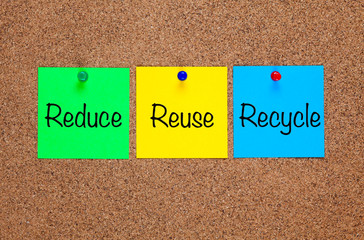 Three paper notes on corkboard with words Reduce, Reuse, Recycle.