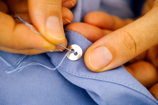 Woman Sewing A Button.