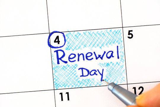 Woman fingers with pen writing reminder Renewal Day in calendar.