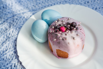 Easter bread, cake and eggs with decor of flowers, beads and nuts. Blue knitted plaid. The concept of the Easter holidays and decor.