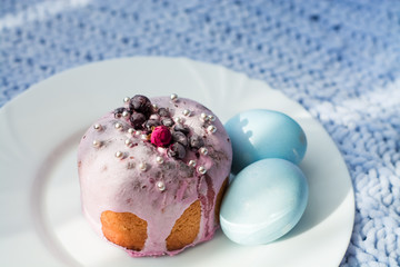 Easter bread, cake and eggs with decor of flowers, beads and nuts. Blue knitted plaid. The concept of the Easter holidays and decor.