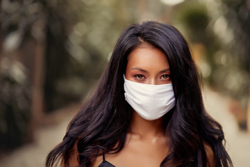 Portrait of beautiful Asian woman wearing surgical face mask protection against virus. Fashion Asian model with white medical mask outdoor