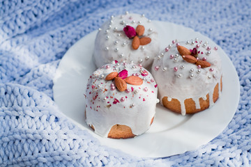 Cake with flowers, beads and nuts. Blue knitted plaid. Cozy Easter, spring still life scene. The concept of the Easter holidays and decor. 