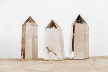 Three smoky natural quartz crystals on a wooden surface on a white background. Copy, empty space for text