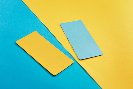 abstract composition of 2 design cards, comparison of two yellow and blue colored cards on a two-color paper background