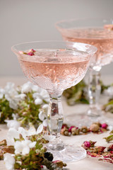 Crystal glasses of pink rose champagne, cider or lemonade with dry rose buds. Blossom cherry...
