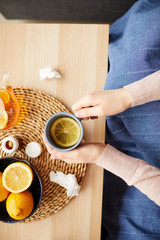 Close-up of woman drinking hot tea with citrus fruits she is ill and treating from disease