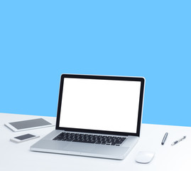 Laptop computer on desk with isolated screen for mockup on blue background. business and technology concept