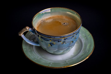 Vintage colorful bright cup of coffee on vintage plate on dark black background