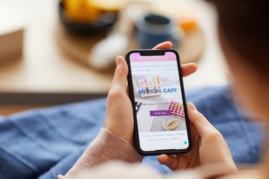 Close-up of woman sitting on sofa and using medical application on her mobile phone at home