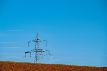 Strommasten über landwirtschaftlich genutztem Feld