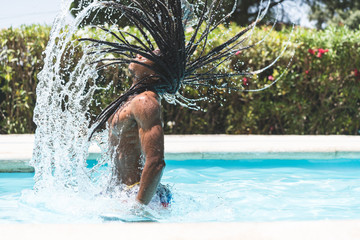 Rastafari Man Throwing Water with his Hair in Swimming Pool. Lifestyle Concept.