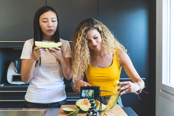 Two Female Bloggers Recording Preparation of Melon at Home.