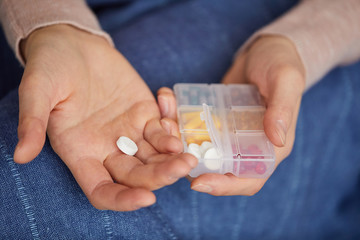 Close-up of woman taking pill out from the box and drinking course from pills for her treatment
