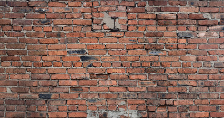 Old brick wall of red blocks with crumbling texture.