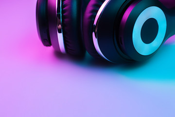 Fototapeta na wymiar Retro 90s style photo of black stylish wireless headphone in neon lights.