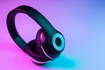 Naklejka premium Retro 90s style photo of black stylish wireless headphone in neon lights.