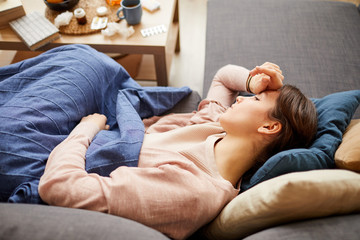 Obraz na płótnie Canvas Sick young woman has a headache she lying on sofa and feeling herself unwell she stay at home