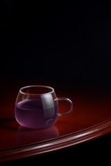 Cup of a purple infusion on a luxurious table with a black background