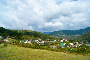 Fototapeta na wymiar Horizontal photo - summer mountain landscape. Mountain villages, domius with colored roofs against the green and blue sky in white clouds