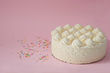 White cream cake on a pink background. Multi-colored sprinkles for cakes. Space for text