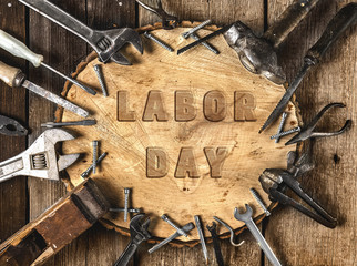 Labor Day. Congratulatory text on an old rustic wooden background surrounded by various tools in the workshop.A greeting card or banner for your store or website.FLat lay.Top view.