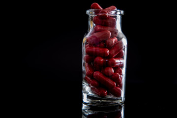 Jar full of red pills on black background 