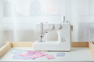 How to sew face mask, protective mask sewing process, pieces of dotted cloth, threads and sewing machine on white table.