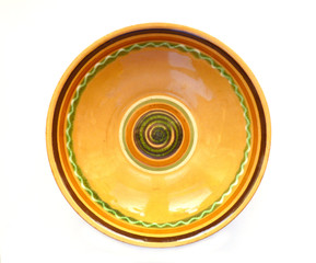 Top view of empty old clay dish with spiral pattern isolated on white. Empty terracotta plate, brown clay serving bowl. 