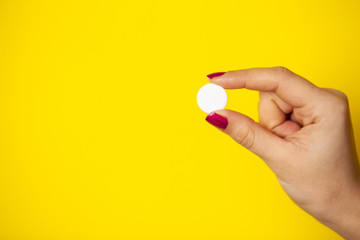 Woman holds white pill in her hand for weight loss