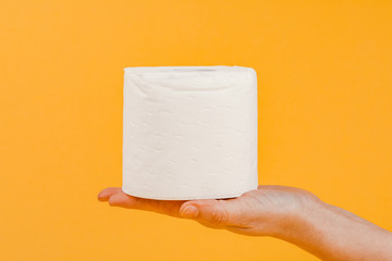 A roll of toilet paper in a woman's hand on a yellow background