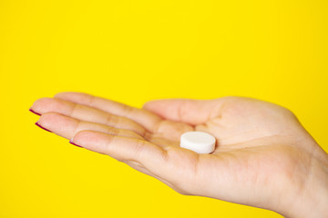 Woman holds white pill in her hand for weight loss