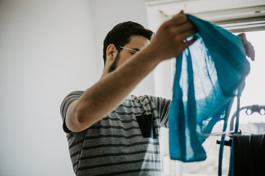 Man doing his laundry at home, washing and folding clothes.