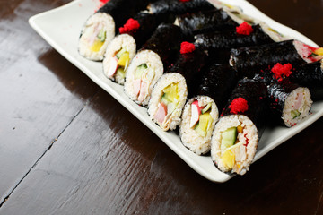 set of Korean rolls in a black shell on a white plate closeup
