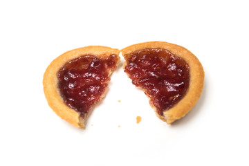 Closeup of crunched mini tartlet with strawberry jam on top view on white background