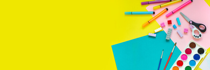 School supplies, stationery on yellow background - space for caption. Child ready to draw with pencils and make application of colored paper. Top view.