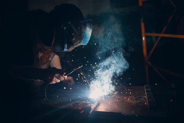 Welder welding metal construction on workshop