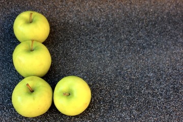 Yellow apples on a gray background. Row of green with one red apple among them on gray background. 4 Thinking out of the box concept. ripe green apples stone table background top view space for text
