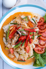 Stir-fried squid with salted egg yolk, onion, spring onion and Chili pepper on white plate. Food concept. Thailand seafood cuisine. thai food