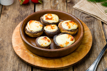 Fototapeta na wymiar mushrooms baked with Suluguni cheese on wooden table